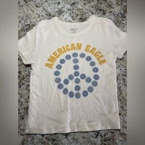 American Eagle Outfitters Cream Tee with Yellow and Blue Peace Design